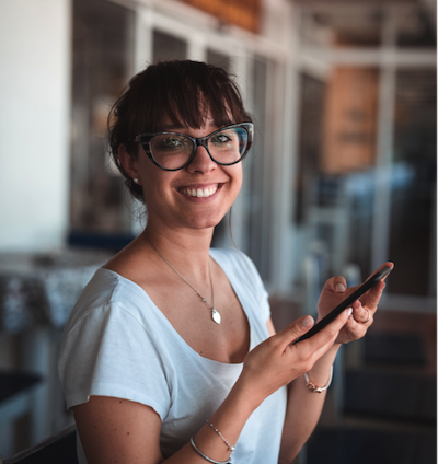 Woman smiling and holding her cell phone Woman smiling and holding her cell phone
