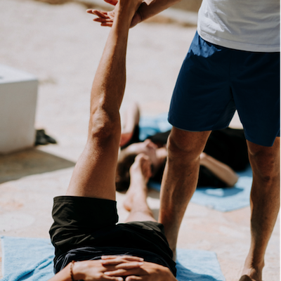 A fitness instructor helping a fitness member stretch their leg A fitness instructor helping a fitness member stretch their leg